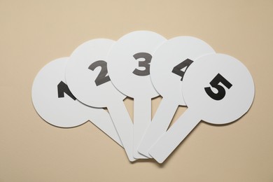 Photo of Auction paddles with numbers on beige background, flat lay