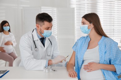 Photo of Doctor vaccinating pregnant woman against Covid-19 in clinic
