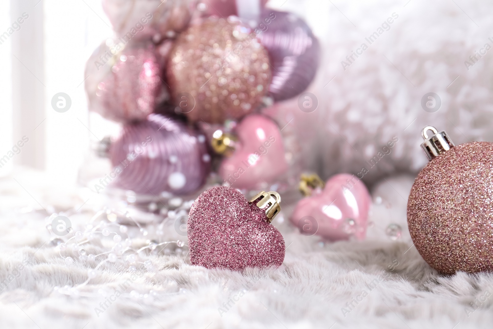Photo of Beautiful pink Christmas baubles on white fur. Space for text
