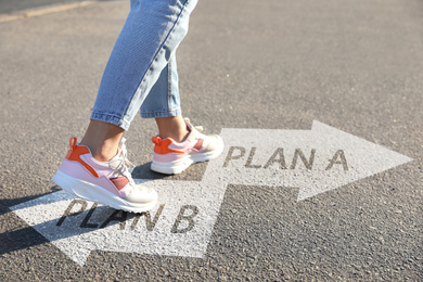 Image of Choosing between Plan A and Plan B. Woman near arrows on road, closeup view