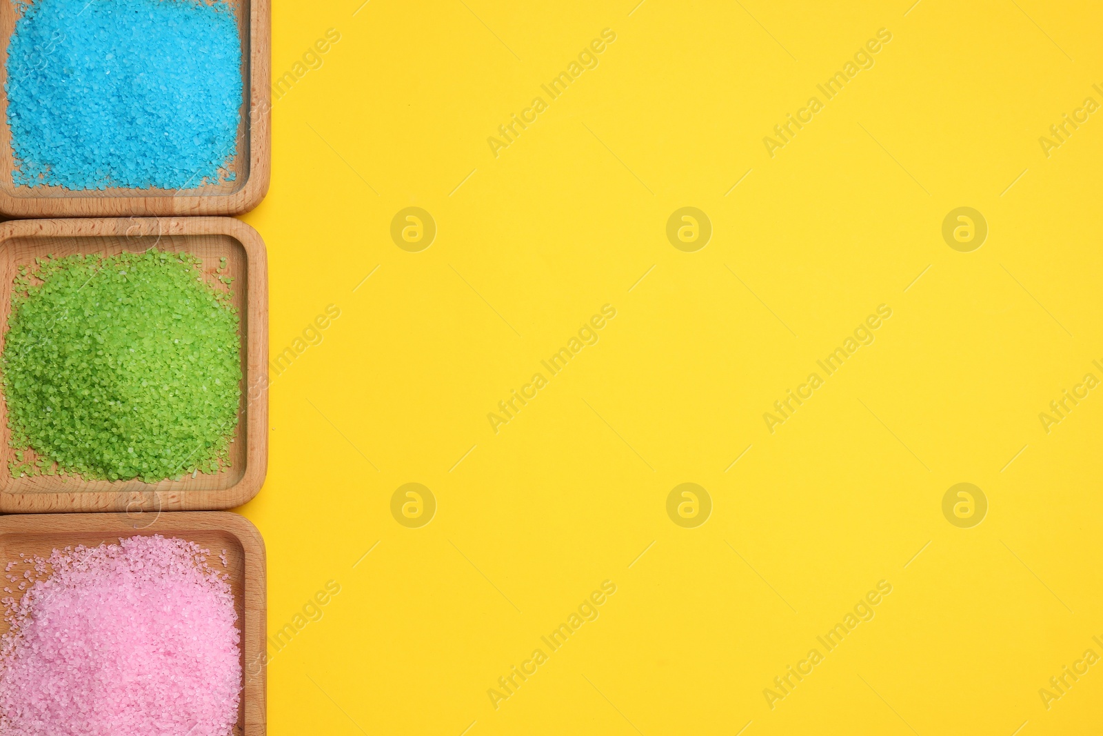 Photo of Different sea salt on yellow background, flat lay. Space for text