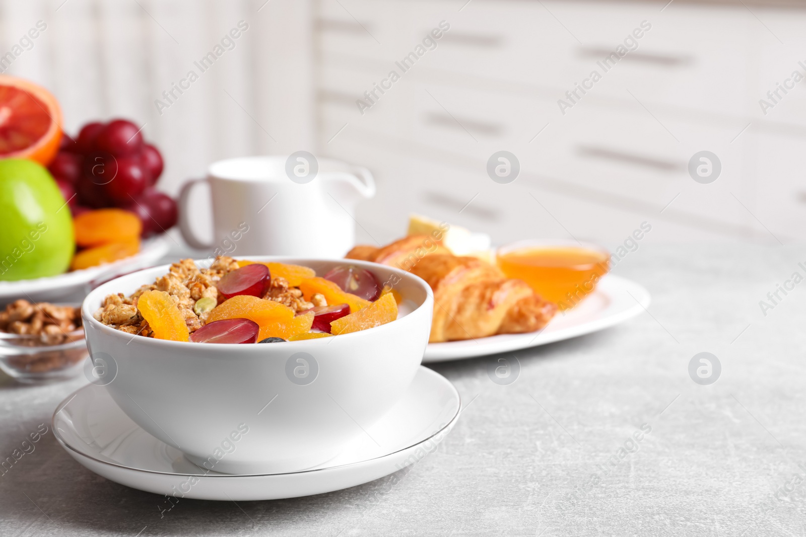 Photo of Delicious granola with fruits on white table. Space for text