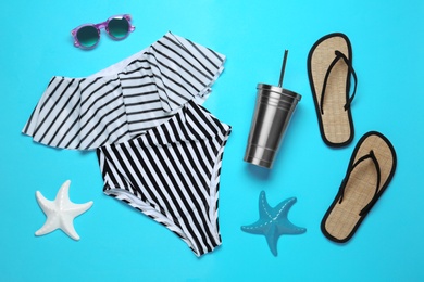 Flat lay composition with women's swimsuit on blue background