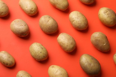 Photo of Many fresh potatoes on red background, flat lay