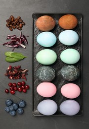 Naturally painted Easter eggs on black table, flat lay. Coffee beans, red cabbage, spinach, hibiscus, cranberries and blueberries used for coloring