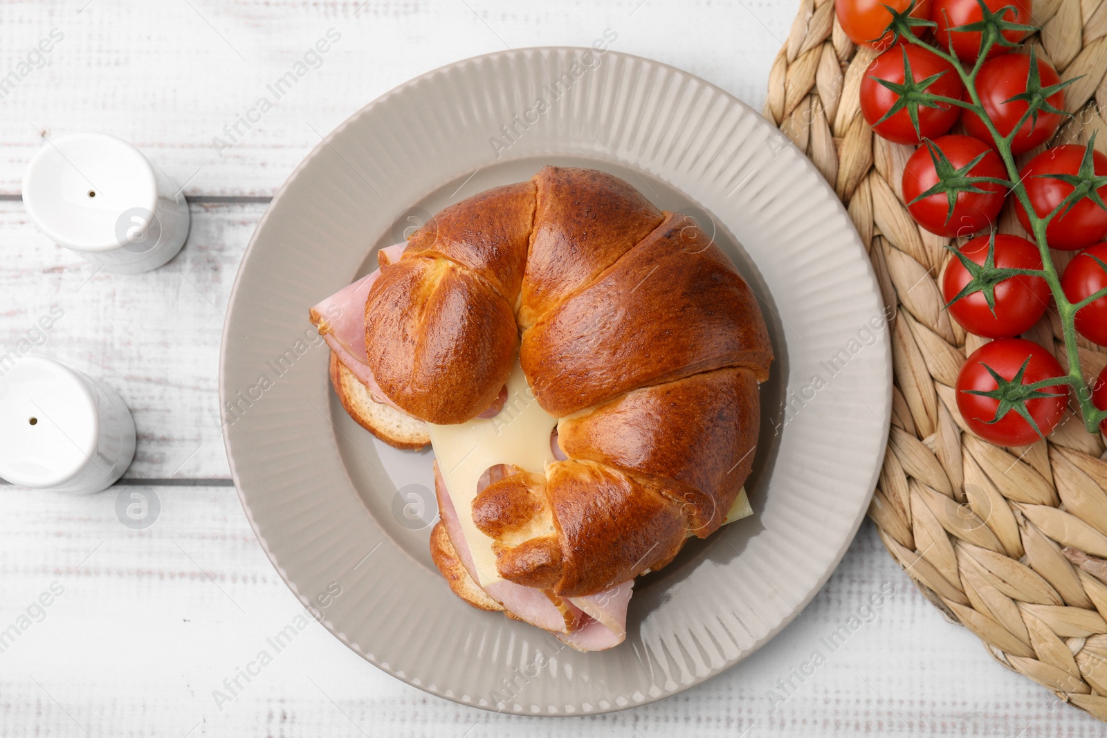 Photo of Tasty crescent roll with ham and cheese on white wooden table, flat lay
