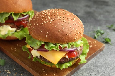 Photo of Delicious burgers with beef patty on grey table, closeup