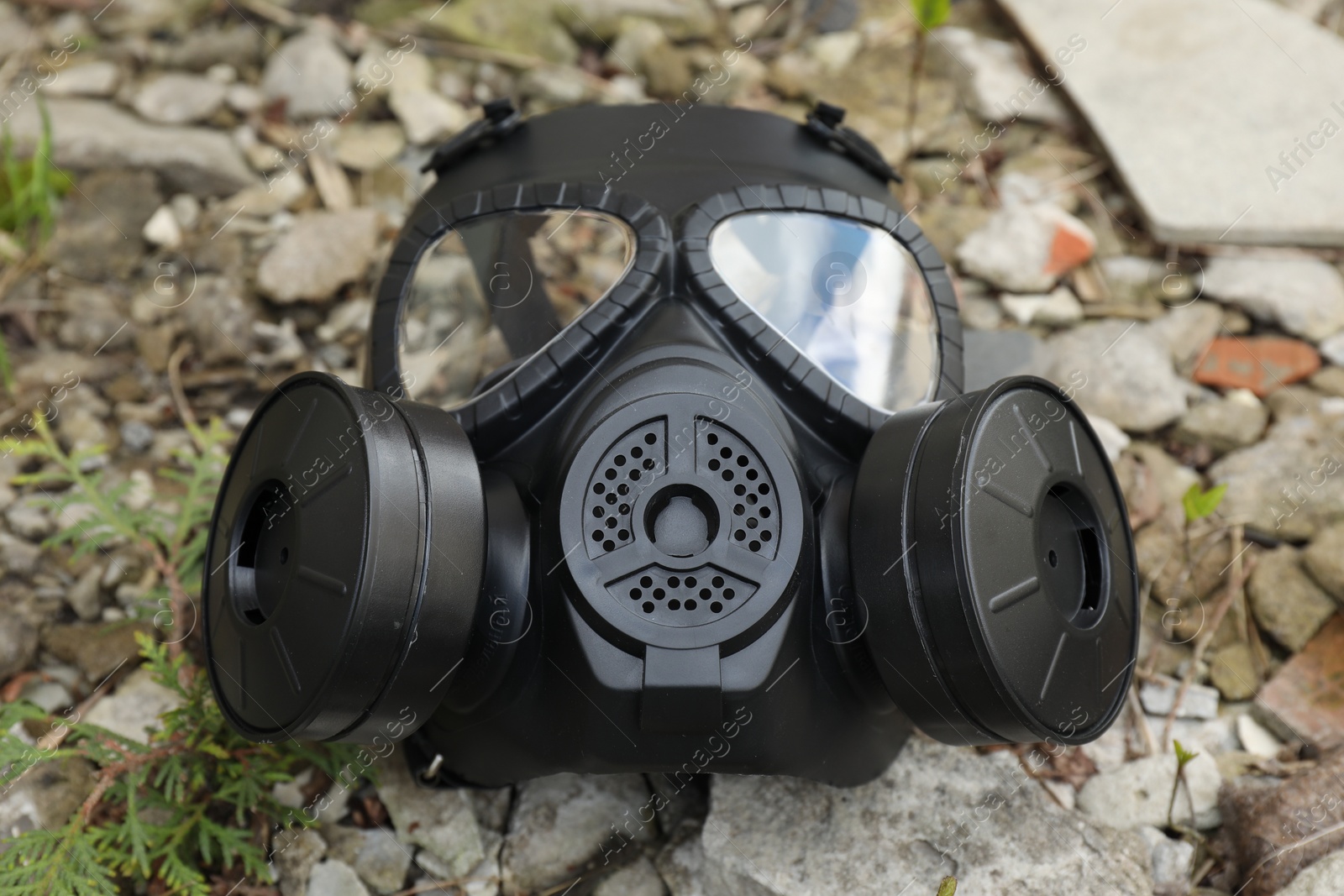 Photo of One gas mask on ground outdoors, closeup