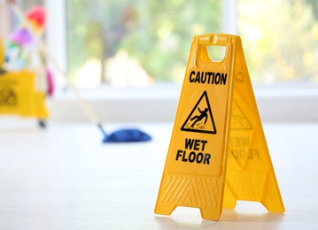 Photo of Safety sign with phrase Caution wet floor, indoors