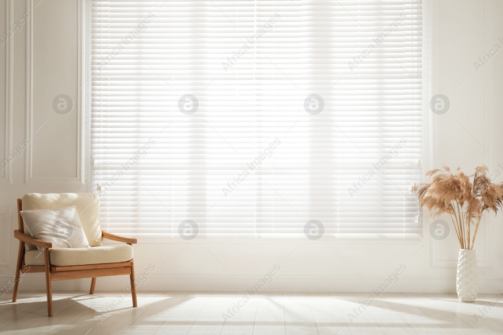 Photo of Cosy armchair and decor near large window with blinds in spacious room. Interior design