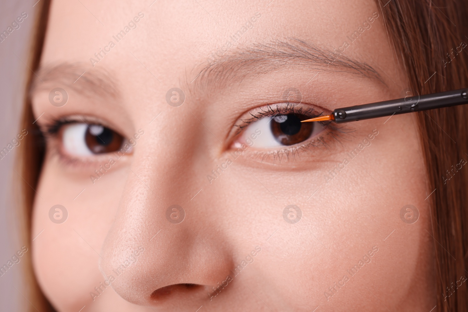 Photo of Woman applying serum onto eyelashes, closeup view