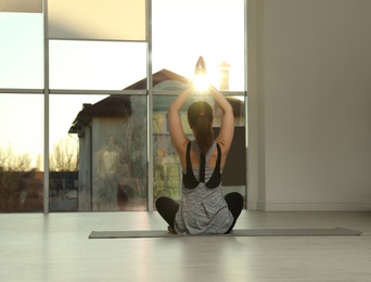 Photo of Young woman practicing yoga in sunlit room