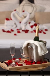 Honeymoon. Sparkling wine and glasses on wooden table in room