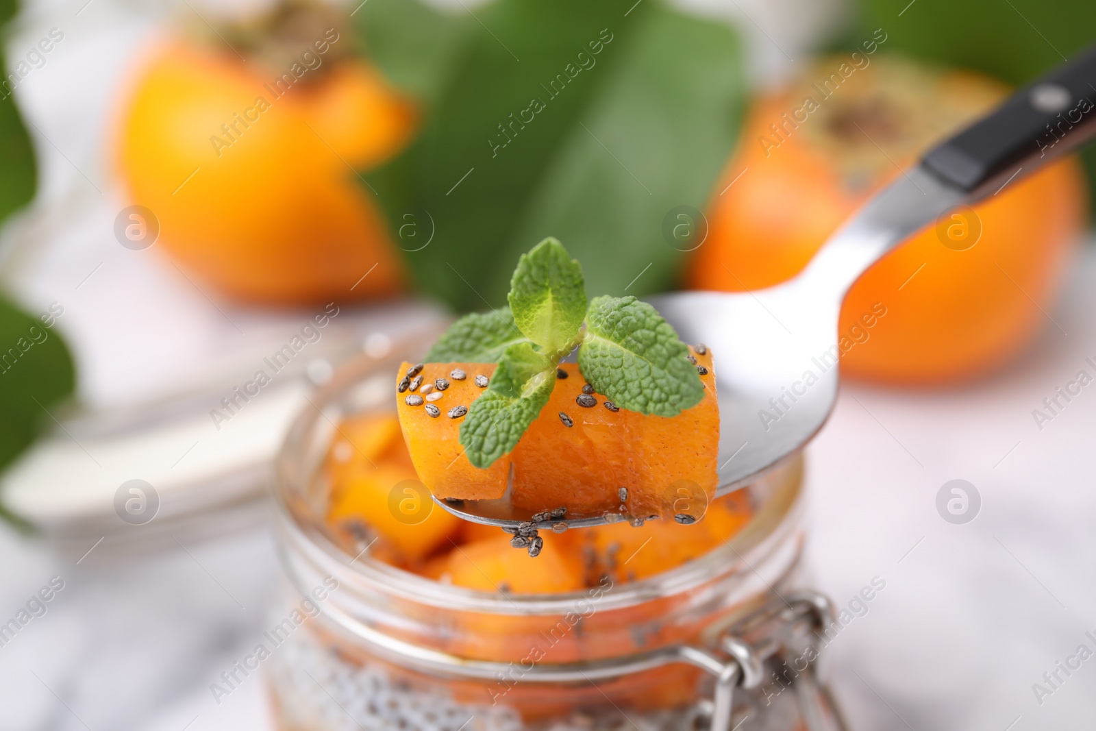 Photo of Taking delicious persimmon dessert with spoon, closeup
