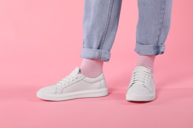 Photo of Woman wearing stylish white sneakers on pink background, closeup