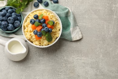 Tasty millet porridge with blueberries, pumpkin and mint in bowl on light grey table, flat lay. Space for text