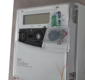 Electricity meter on light grey wall against white background