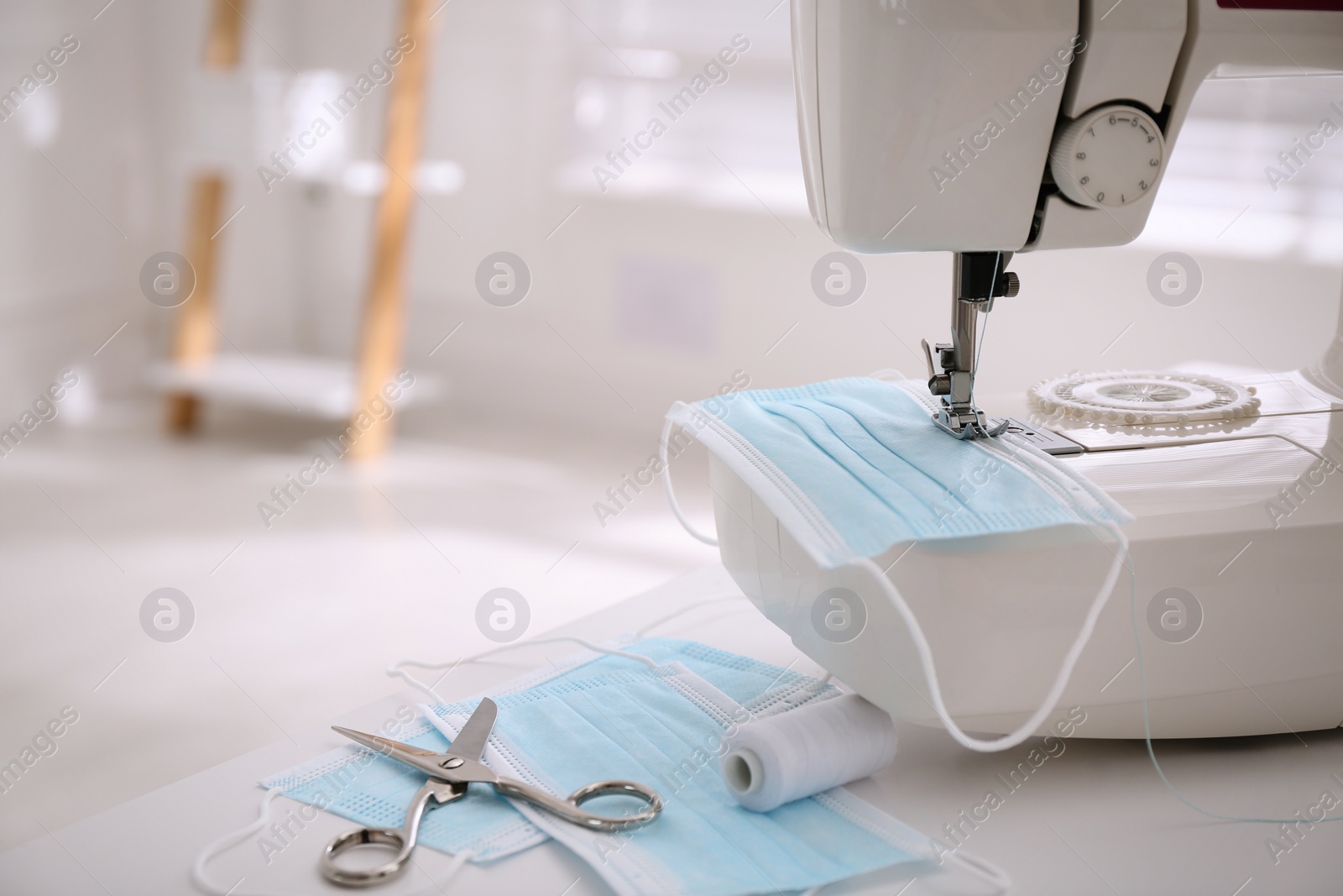 Photo of Sewing machine with disposable face mask on table indoors, space for text