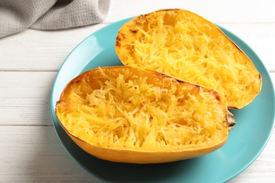 Plate with cooked spaghetti squash on white wooden background