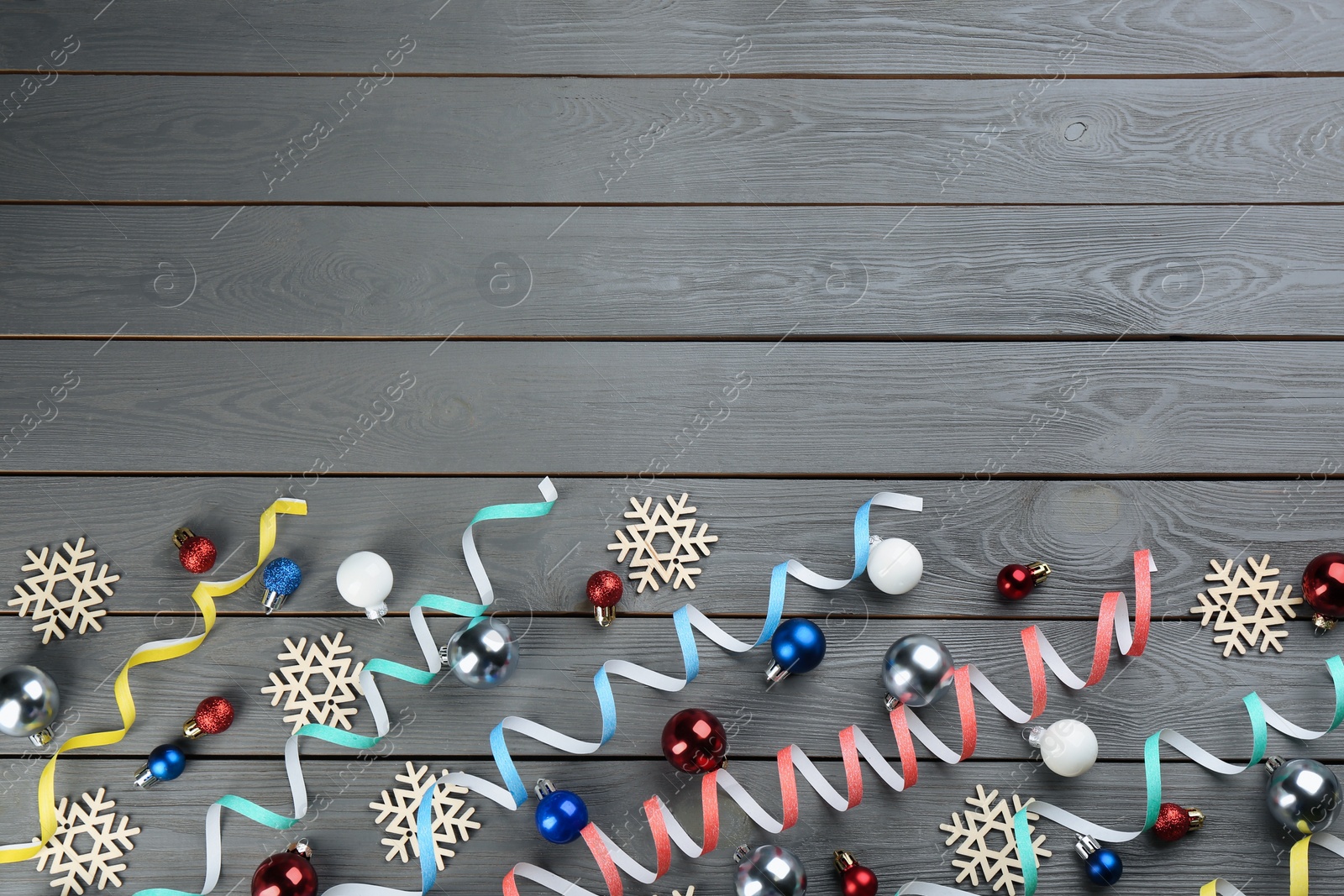 Photo of Flat lay composition with serpentine streamers on grey wooden background, space for text