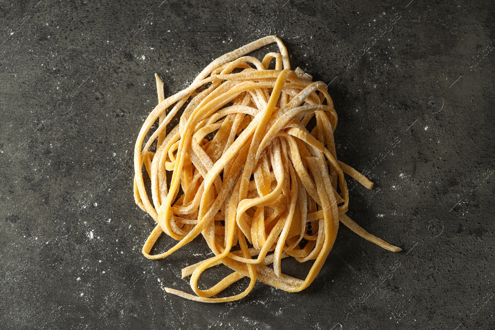 Photo of Uncooked homemade pasta on dark grey table, top view