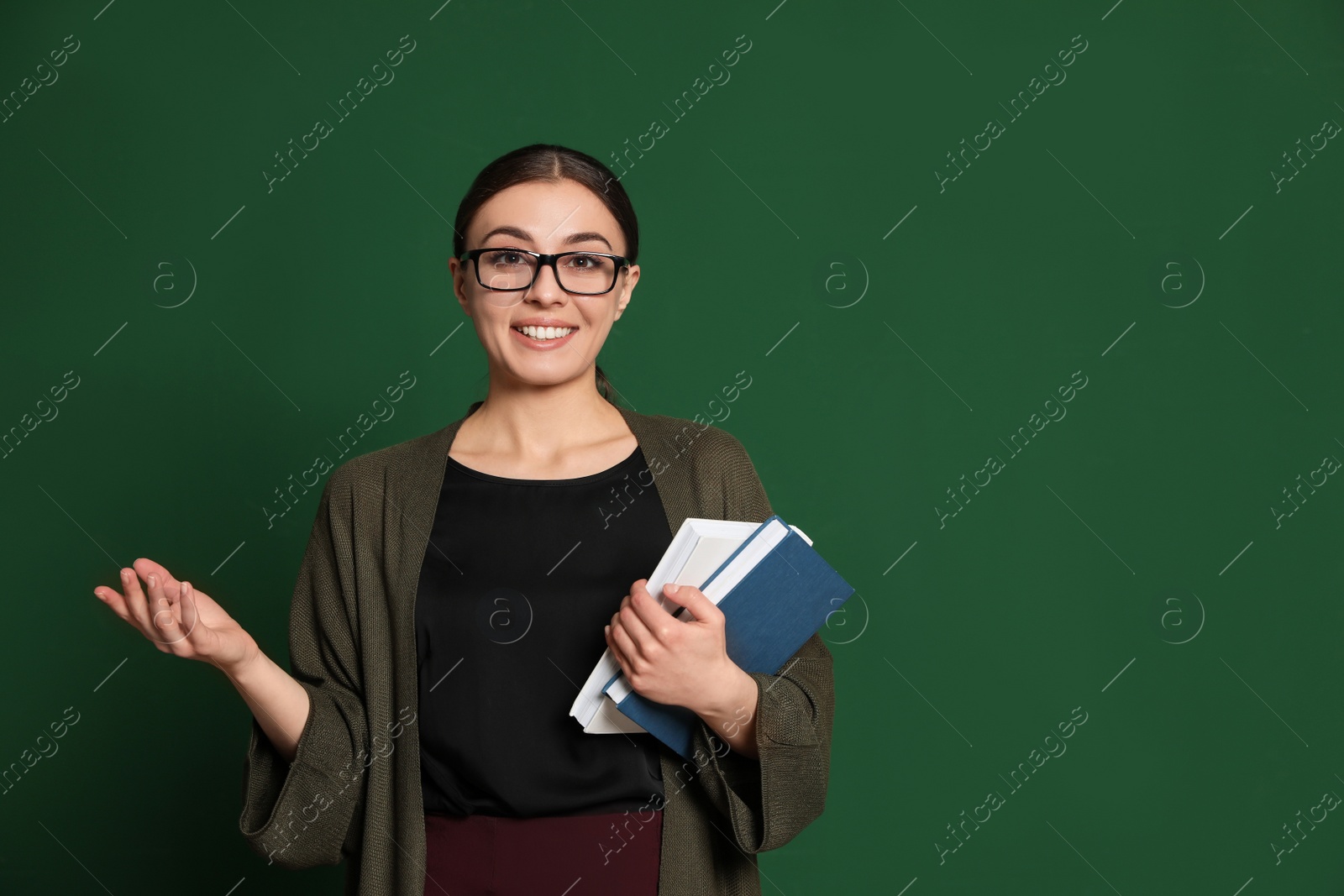 Photo of Portrait of young teacher with books on green background. Space for text