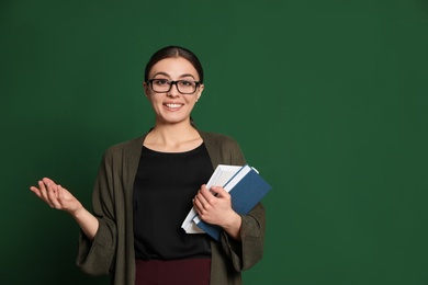 Portrait of young teacher with books on green background. Space for text