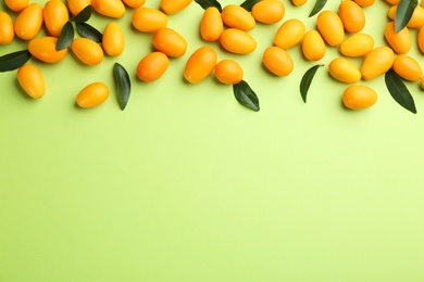 Photo of Fresh ripe kumquats on light green background, flat lay. Space for text