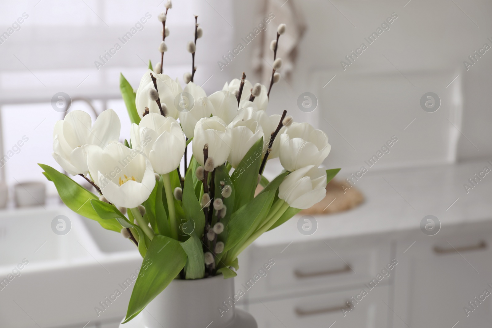 Photo of Beautiful bouquet of willow branches and tulips in vase indoors, space for text