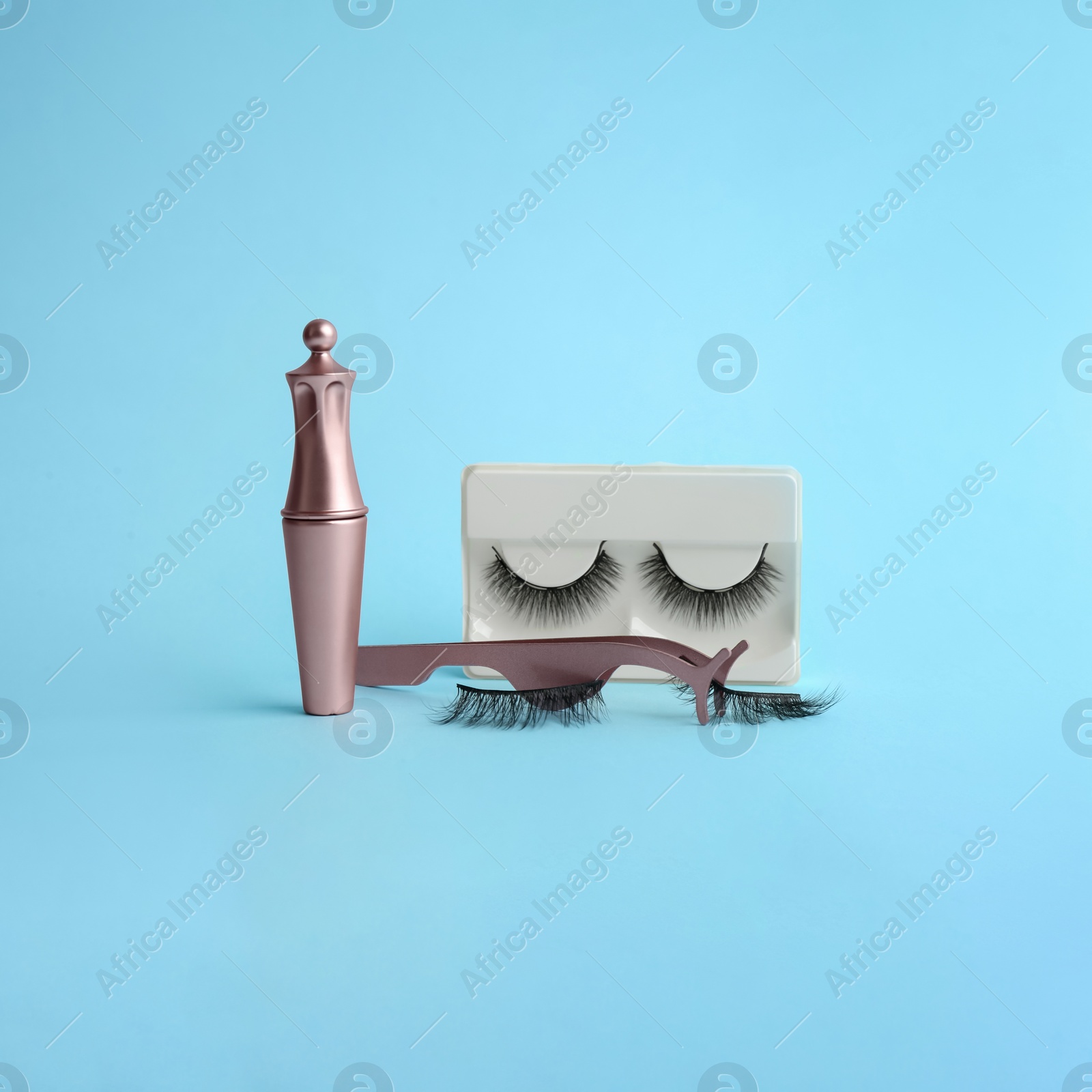 Photo of Magnetic eyelashes and accessories on light blue background