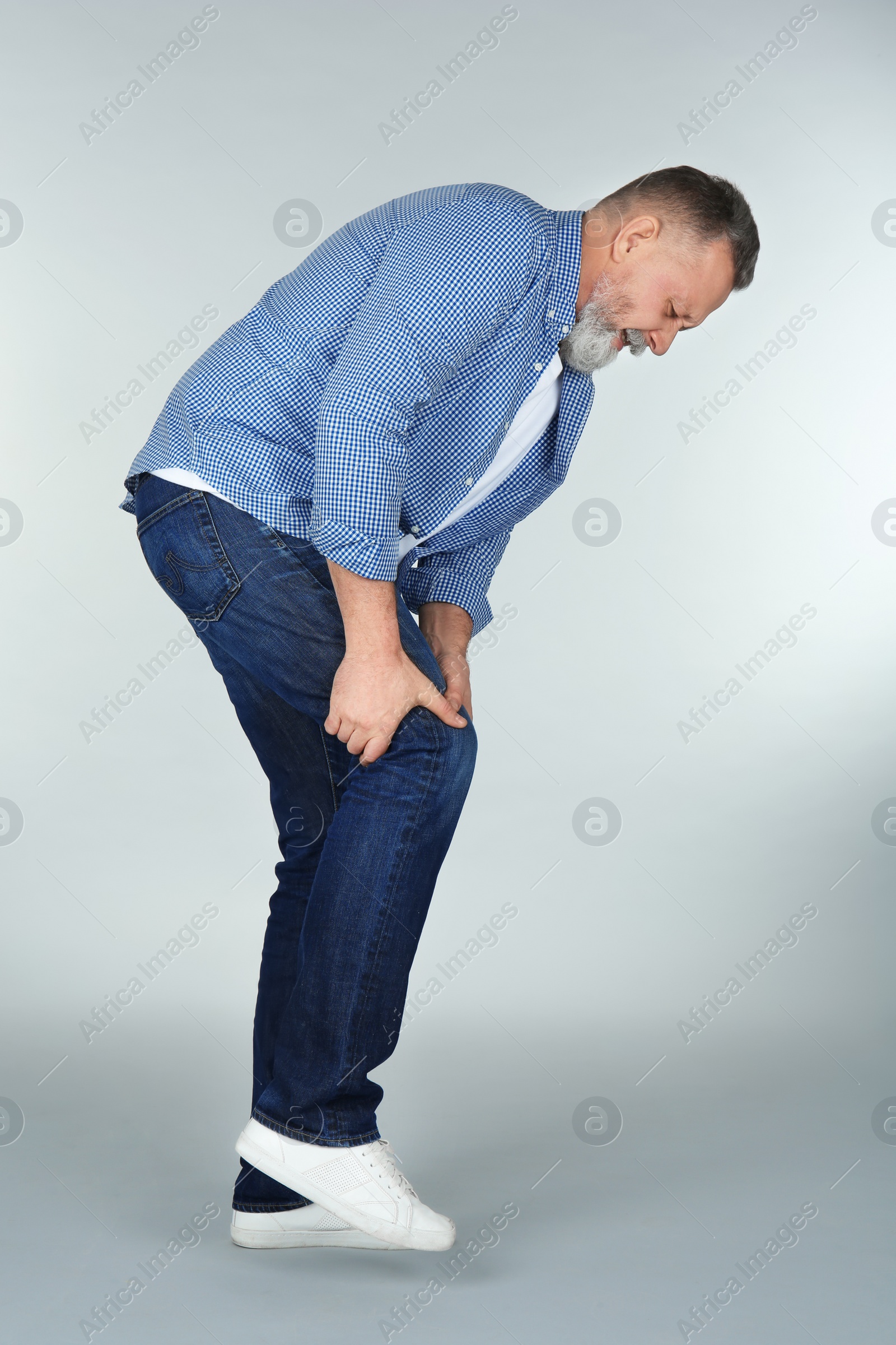 Photo of Man suffering from knee pain on light background