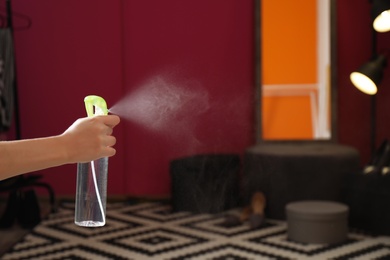 Photo of Woman spraying air freshener at home