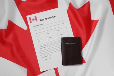 Photo of Immigration to Canada. Visa application form and passport on flag, flat lay