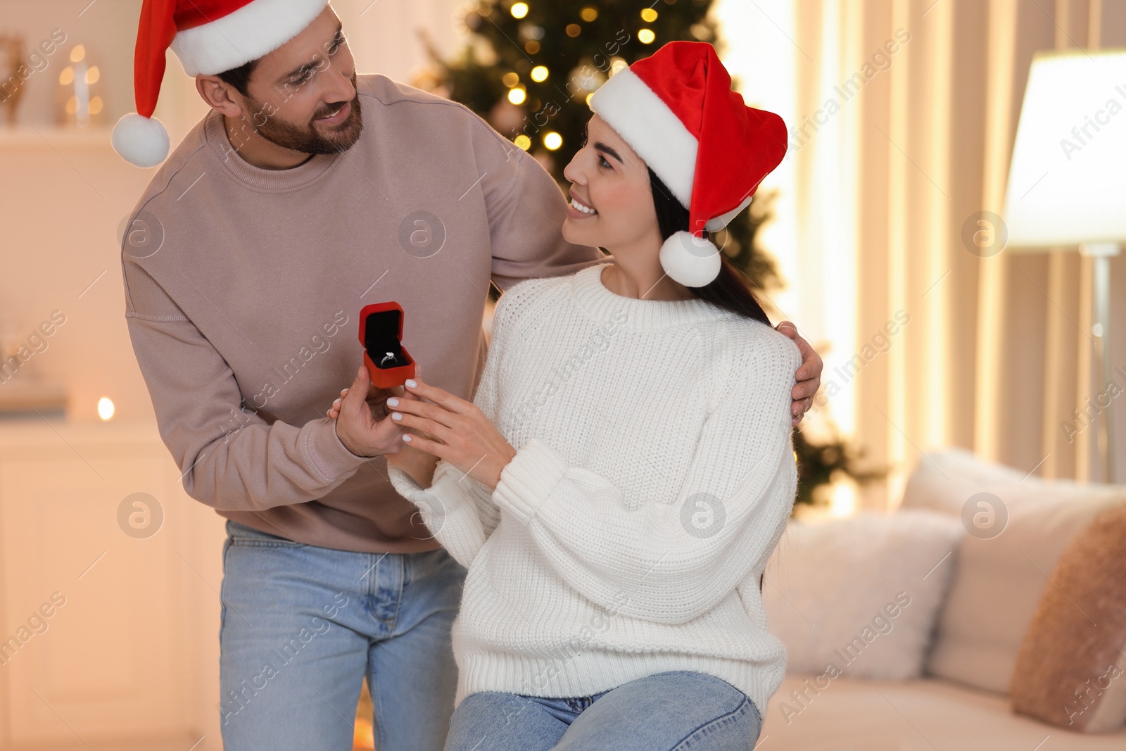 Photo of Making proposal. Man with engagement ring surprising his girlfriend at home on Christmas