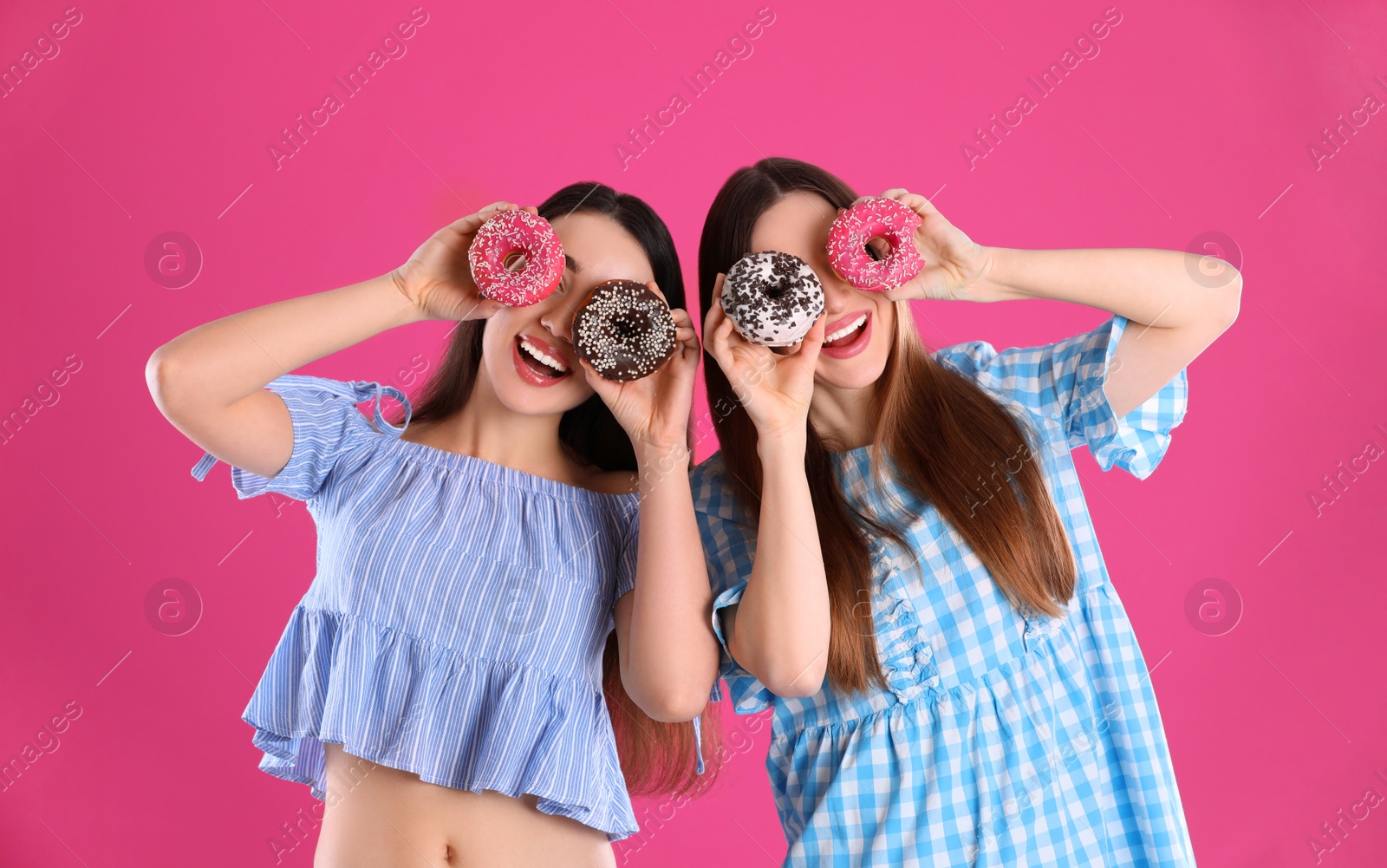 Photo of Beautiful young women with donuts on pink background