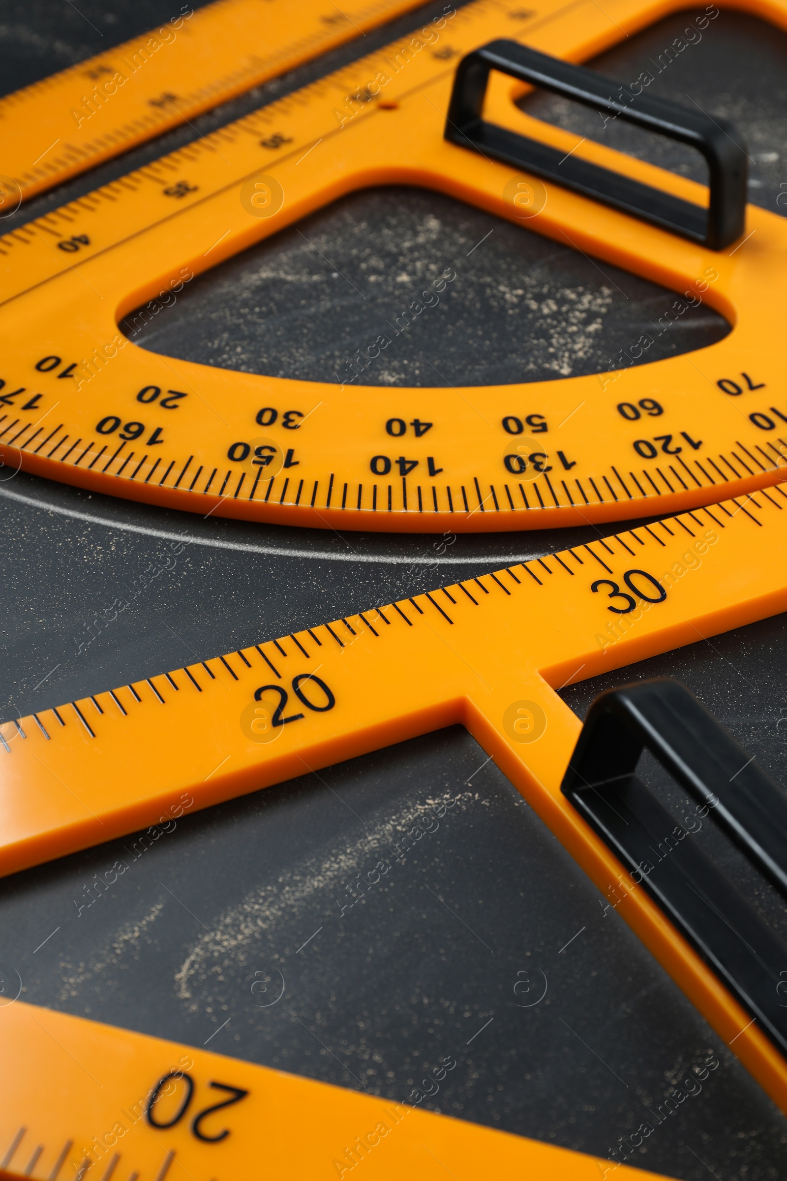 Photo of Protractor, ruler and triangle with measuring length and degrees markings on blackboard