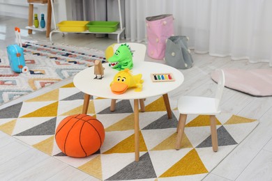 Different toys on white table and chairs in playroom. Kindergarten interior design