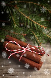 Cinnamon sticks and fir tree branches on wooden table, closeup