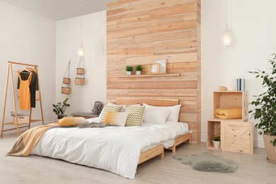 Photo of Stylish room interior with comfortable bed near wooden wall