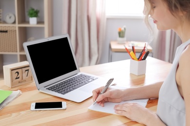 Photo of Young woman working with laptop at desk. Home office