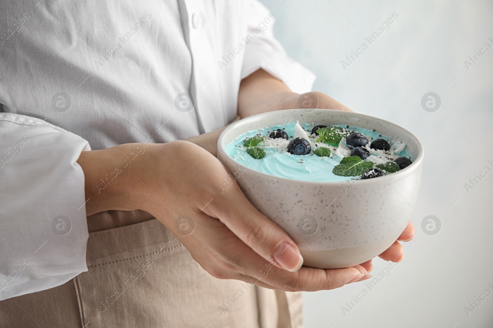 Photo of Woman holding bowl of spirulina smoothie, closeup
