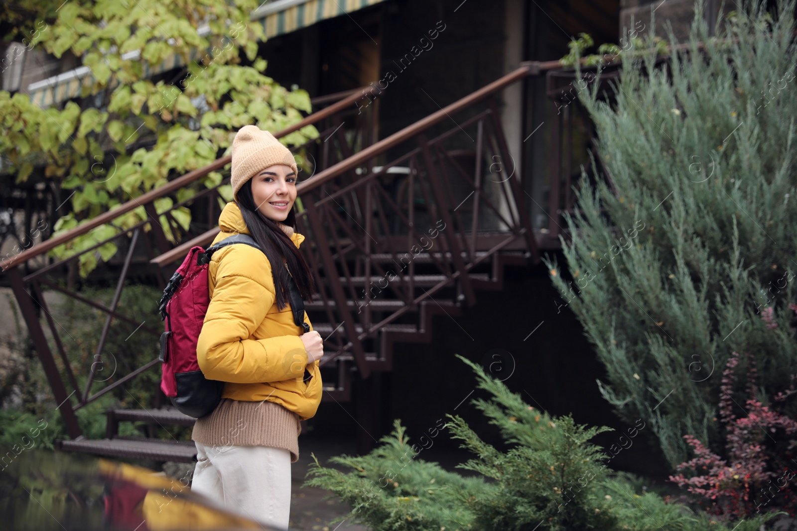 Photo of Female tourist with travel backpack on city street. Urban trip