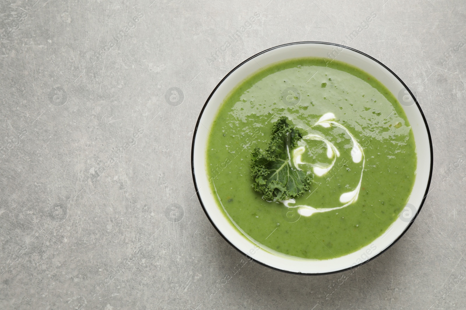 Photo of Tasty kale soup on grey table, top view. Space for text