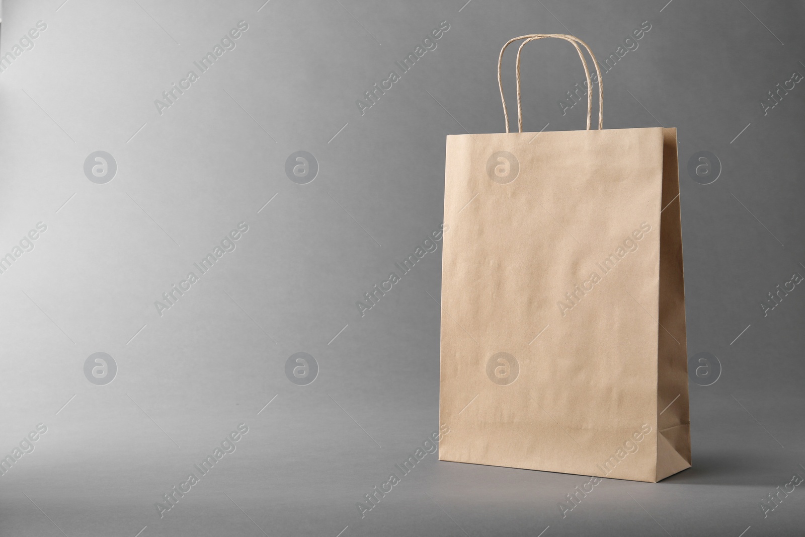 Photo of One kraft paper bag on grey background, space for text. Mockup for design