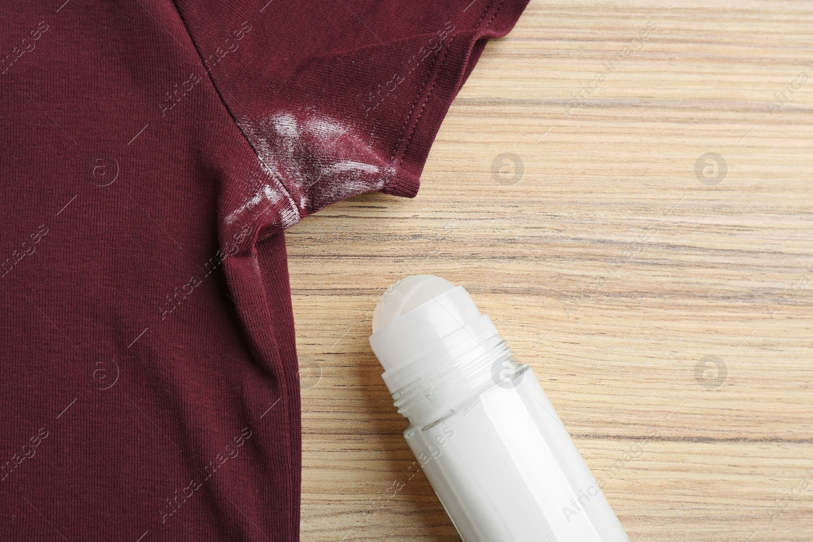 Photo of Clothes with stain and deodorant on wooden background, closeup