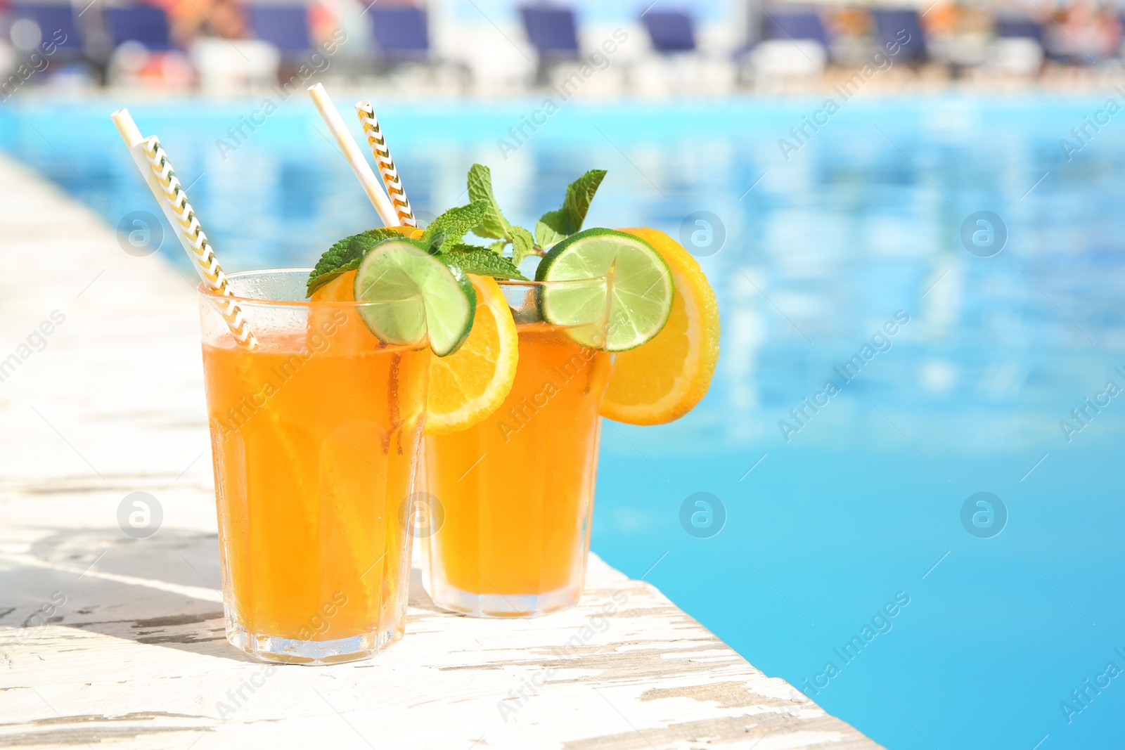 Photo of Refreshing cocktail in glasses near outdoor swimming pool on sunny day