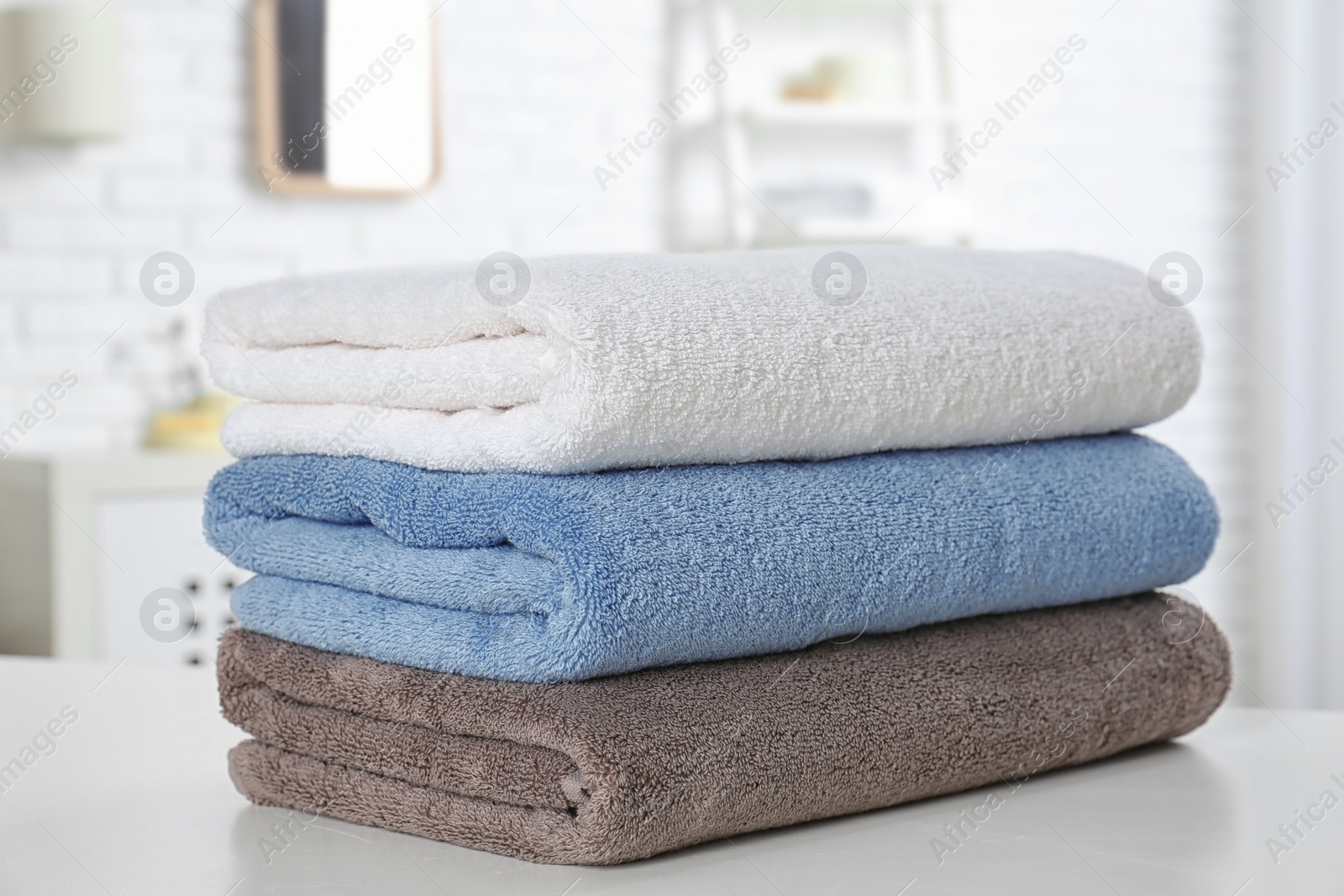 Photo of Stack of fresh towels on table in bathroom, closeup