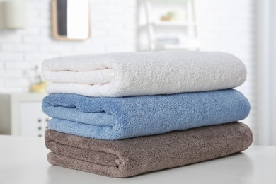 Stack of fresh towels on table in bathroom, closeup