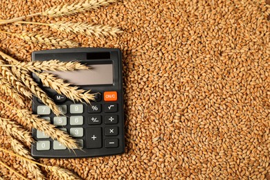 Photo of Calculator and wheat ears on grains, top view. Agricultural business