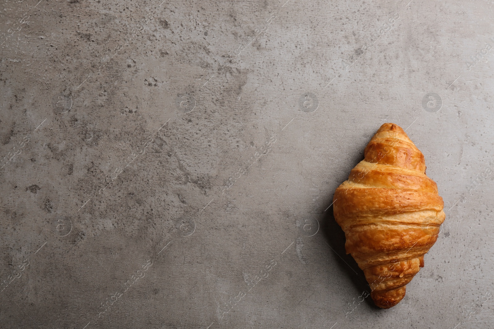 Photo of Tasty croissant and space for text on grey background, top view. French pastry